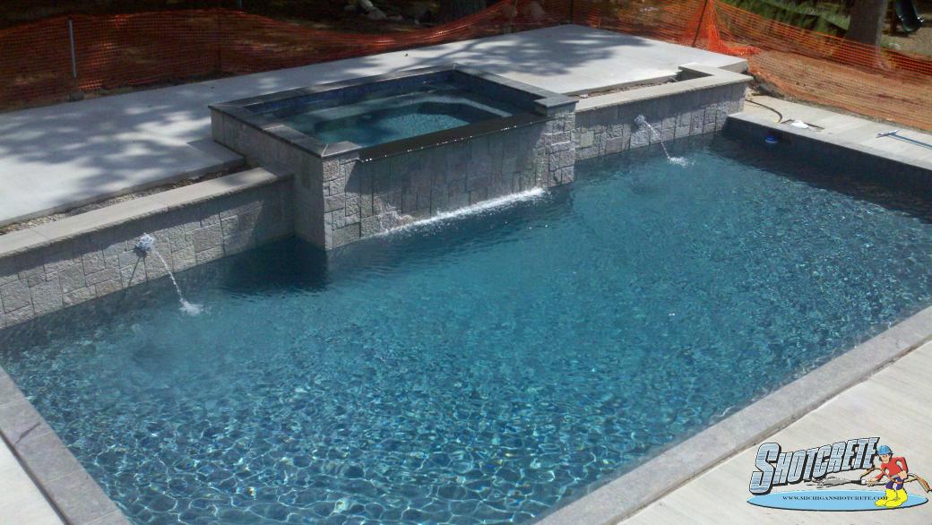 Custom pool in Milford, Mi Spillover spa and pebble coating